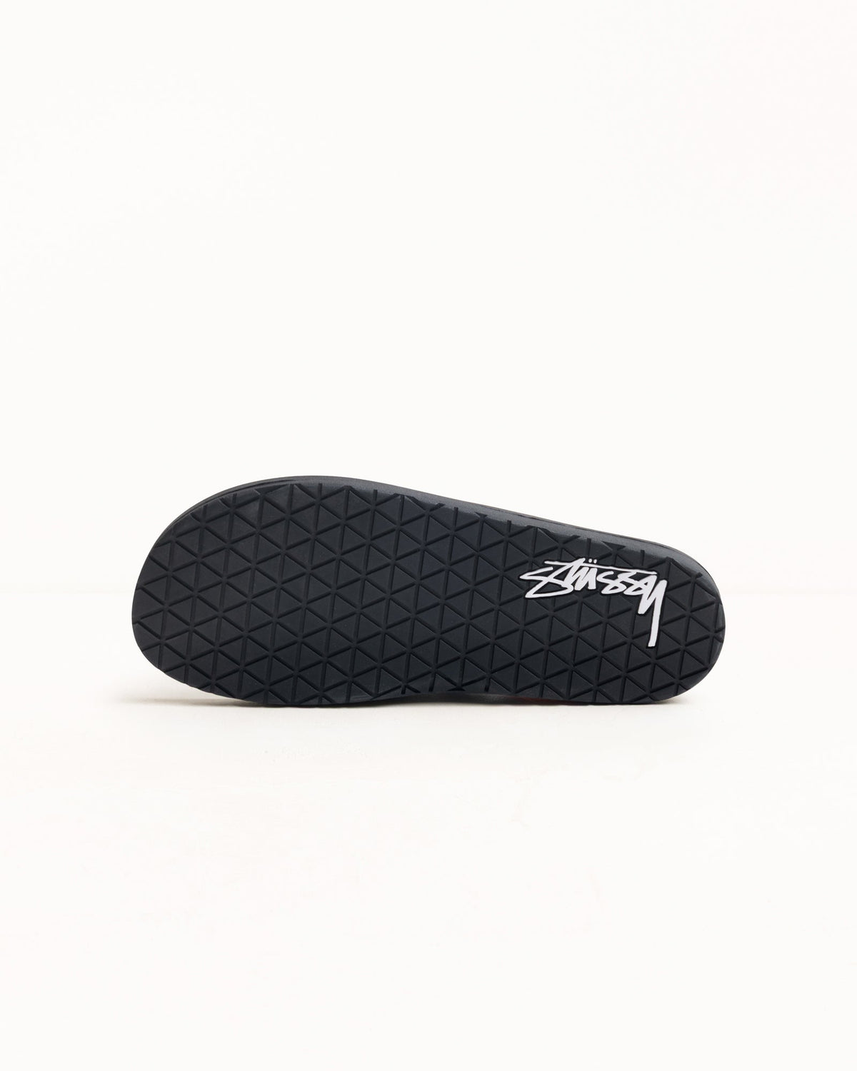 Rubber flip-flop in black, outsole view with diamond tread and white logo