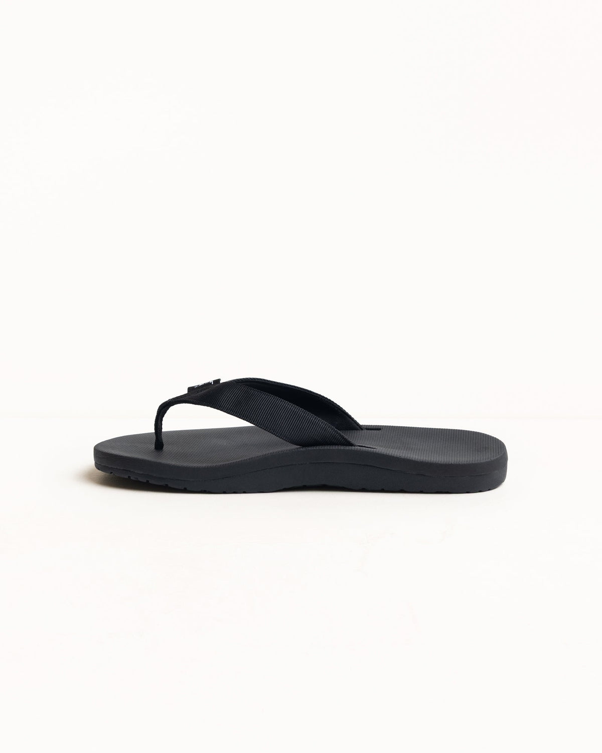 Rubber flip-flop in Black with wide nylon webbing strap and textured, contoured sole